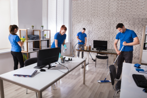 group of janitors cleaning the modern office with caution wet floor sign